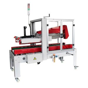 Precintadora de cajas automática RUBBER con plegador de solapas rojo bajo su cubierta de seguridad transparente